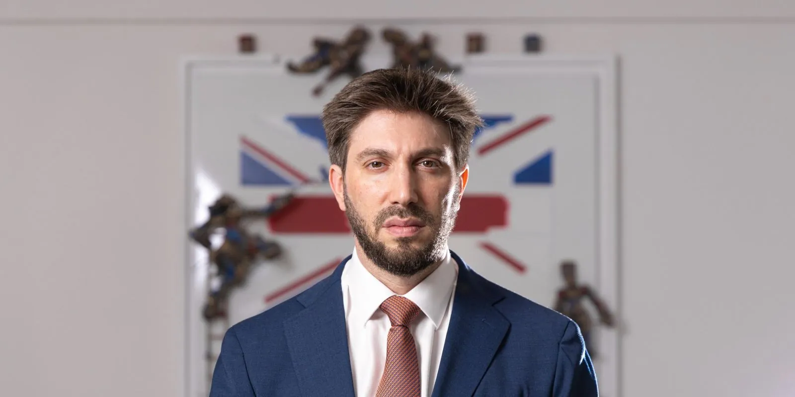 Daniel Seal in a navy suit, standing in front of a Union Jack artwork in London