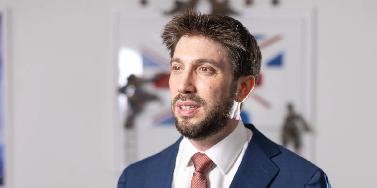 Daniel Seal speaking, in a navy suit and pink tie