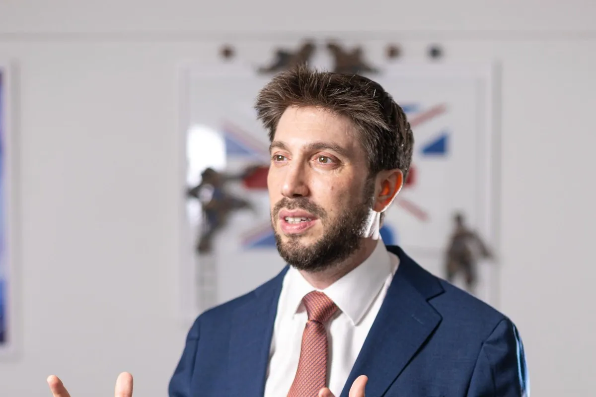 Daniel Seal speaking, in a navy suit and pink tie